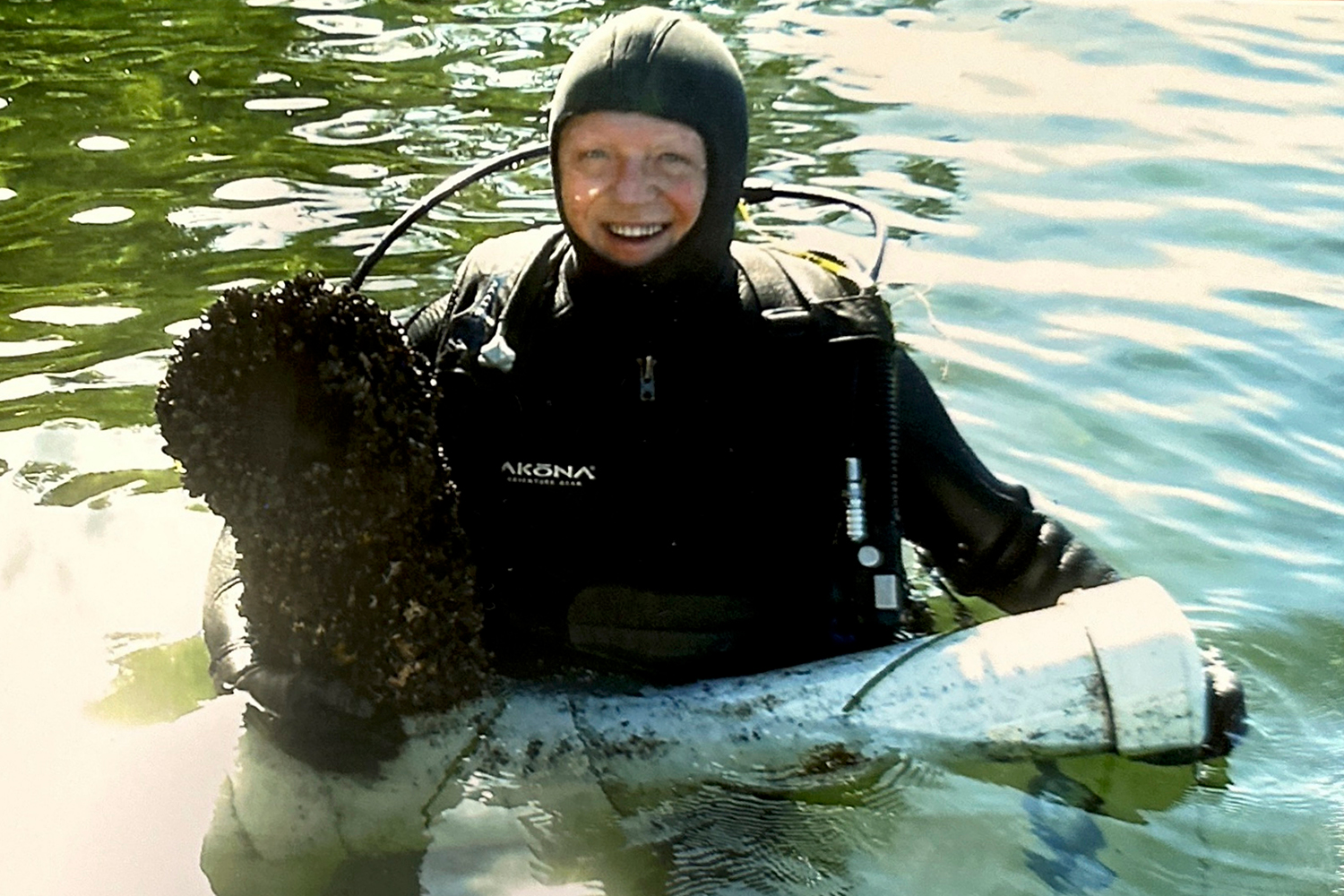 a SCUBA diver holding a clogged zebra mussel filter system in a lake